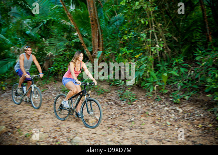 Couple riding bicycles on jungle path Stock Photo
