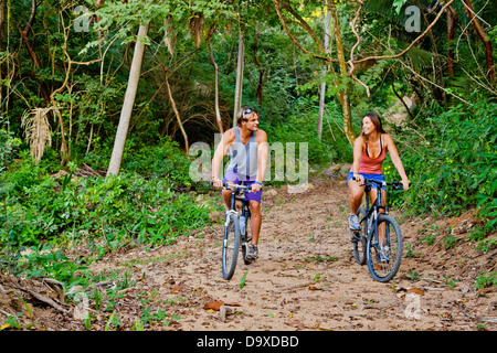 Couple riding bicycles on jungle path Stock Photo