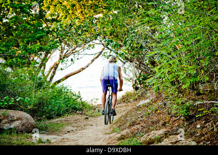 Man riding bicycle on path to beach Stock Photo