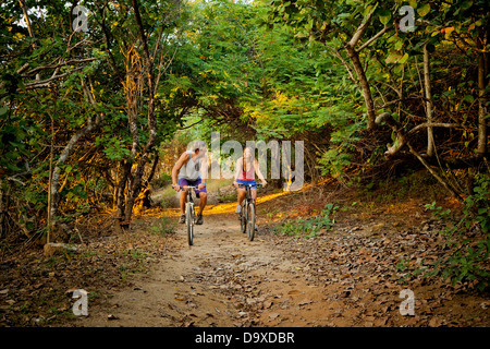 Couple riding bicycles on path to beach Stock Photo