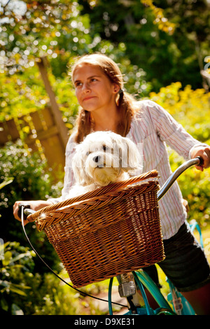 Teen girl on bike with dog in basket Stock Photo