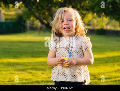 Little girl with naughty expression. The girl is sticking her tongue out and her expression is funny. Stock Photo