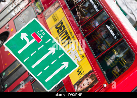 A red London Bus passes a Bus Lane sign in the city centre. Stock Photo