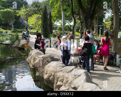 dh Hong Kong Park CENTRAL HONG KONG Woman tourists at Hong Kong Park lake photographing fish tourist ponds Stock Photo