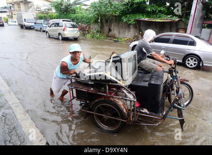 Davao, Philipinnes. 28th June 2013. Filipino residents carrying their television set maneuvers as they try to pass in a flooded road cause by a heavy downpour of rain in Davao city, Southern Philippines, 28 June 2013. According to Philippine Atmospheric Geophysical and Astronomical Services Administration (PAGASA), Storm Signal Number One is raised in areas of Visayas and Mindanao as tropical depression 'Gorio' enters Philippine territory. Credit:  Eli Ritchie Tongo/Alamy Live News Stock Photo