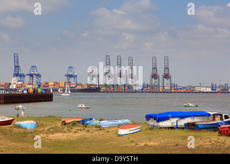 Small boats on seashore with in Felixstowe container port across river Orwell estuary from Harwich Essex England UK Britain Stock Photo