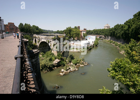 People walking on the bridge across Tiber River near remains of Ponte Rotto (Broken Bridge), ancient Rome’s ﬁrst stone bridge Stock Photo