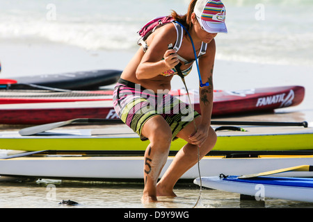 Female Paddle boarder checks out her board ready for the race at Siesta Key beach FL Stock Photo