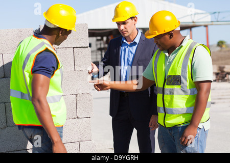 construction workers with their manager checking bricks quality Stock Photo