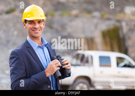 portrait of smiling mine manager with binoculars visiting mining site Stock Photo