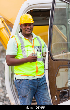 African road construction worker on bulldozer and holding a walkie talkie Stock Photo