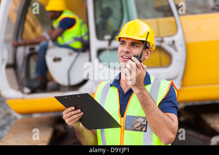 construction foreman talking on walkie-talkie holding clipboard Stock Photo