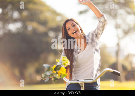 cheerful young woman having fun riding a bike outdoors Stock Photo