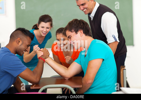 high school teenage boys arm wrestling in classroom Stock Photo