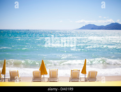 Row of yellow umbrellas and beach chairs on Mediterranean. Stock Photo