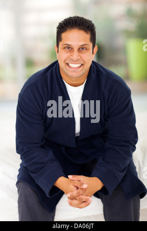 handsome indian man in pajamas sitting on bed Stock Photo