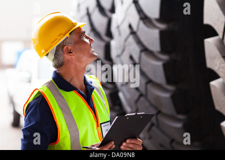 warehouse middle aged worker inspecting industrial tires before exporting Stock Photo