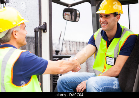 two warehouse forklift drivers handshaking when shift change over Stock Photo