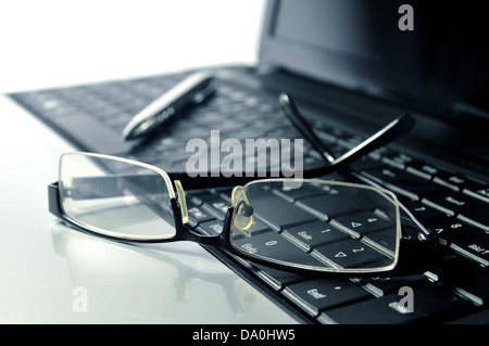 Business - Glasses and ball pen on top of a laptop Stock Photo