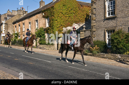 Racehorses being ridden through Middleham, North Yorkshire, on their way back from training gallops. Stock Photo