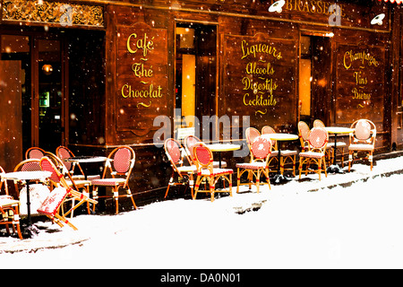 Wooden parisian coffee house with it's sidewalk tables and chairs in winter with the snow falling Stock Photo