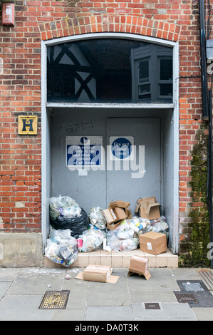 Rubbish piled up against a fire exit door despite signs ordering it to be kept clear making a health and safety violation Stock Photo