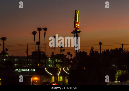 A McDonalds Restaurant along Highway 99 in California's Central Valley just after Sunset with tall Palm Trees in the Background Stock Photo