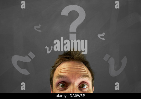Mans head with chalk question marks on a blackboard. Stock Photo