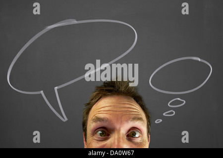 Mans head with chalk thought bubbles on a blackboard. Stock Photo