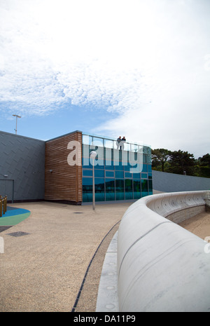 Porth Eirias Centre, Colwyn Bay showing two storey glass section of the building and sea defences and people on viewing platform Stock Photo