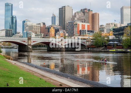 Rowers exercise along the Yarra River near the Princes Bridge in the central business district of Melbourne, Australia. Stock Photo