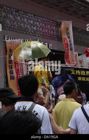 Hong Kong. 1st July 2013. Hong Kong pro--democracy activist advises marchers to use umbrellas during the July 1 march for universal suffrage. Typhoon Rumbia was approaching and at 14h25 HK time, it began to rain heavily © Robert SC Kemp/Alamy Live News. Credit:  Robert SC Kemp/Alamy Live News Stock Photo