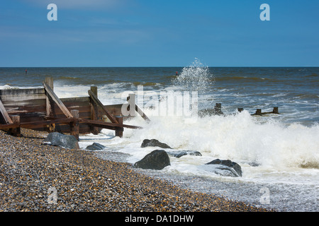 Groynes to prevent coastal erosion with waves breaking onto a shingle beach. This stretch is at Cromer on the Norfolk coast. Stock Photo