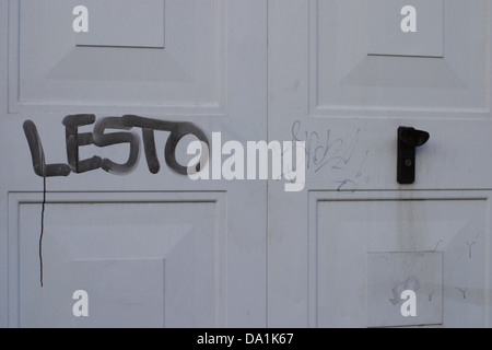 white Back Gate with spray painted grafitti, , door handle, graffiti is black spray painted on. Stock Photo
