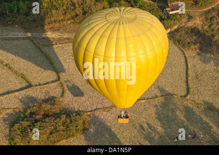 Horizontal aerial view of a hot air balloon landing in the countryside near Vang Vieng. Stock Photo