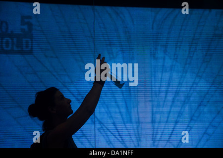 A silhouette of a woman standing in front of a wall of screens take a picture with smartPhone. Stock Photo