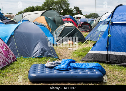 Arrivals - the sun soon fades and the rain starts. People bring everything but to help there is even an inflate you bed service Stock Photo