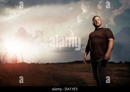 Man standing in front of sunset in open field Stock Photo