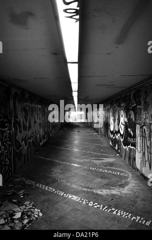 Dark pedestrian underpass with smashed tiles and smudged walls. Black and white. Stock Photo