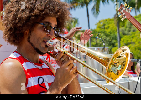 Man with afro hair style playing trombone while marching in the summer solstice paraded in Santa Barbara, California Stock Photo