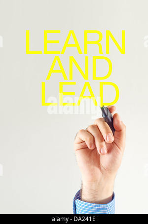 Learn and lead. Businessman writing with yellow marker pen on the screen Stock Photo