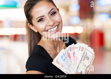 happy young woman holding fan of cash on casino background Stock Photo