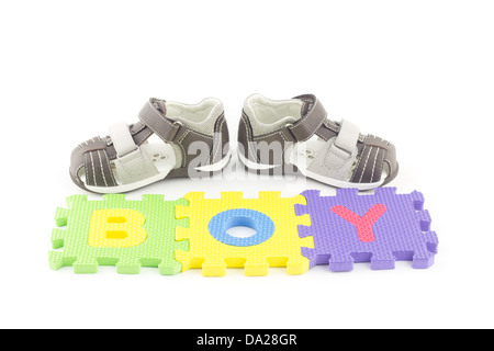 Sandals of a toddler in front of alphabet puzzle pieces isolated on white background Stock Photo