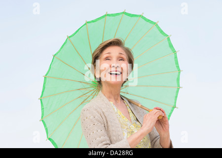 Portrait of senior woman holding green parasol Stock Photo