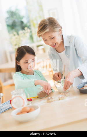 Granddaughter (8-9) cooking with grandmother Stock Photo