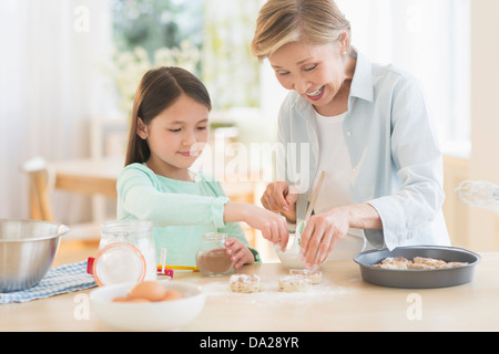 Granddaughter (8-9) cooking with grandmother Stock Photo