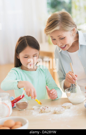 Granddaughter (8-9) cooking with grandmother Stock Photo