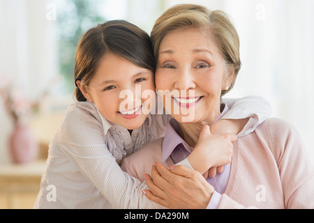 Granddaughter (8-9) embracing grandmother Stock Photo
