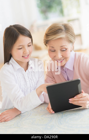 Granddaughter (8-9) and grandmother using digital tablet Stock Photo