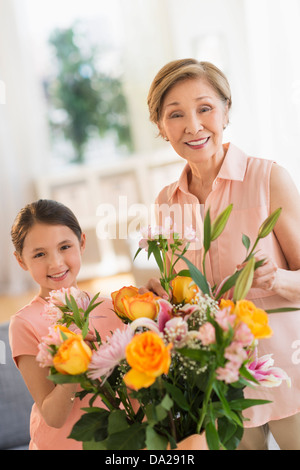 Granddaughter (8-9) and grandmother arranging flowers at home Stock Photo